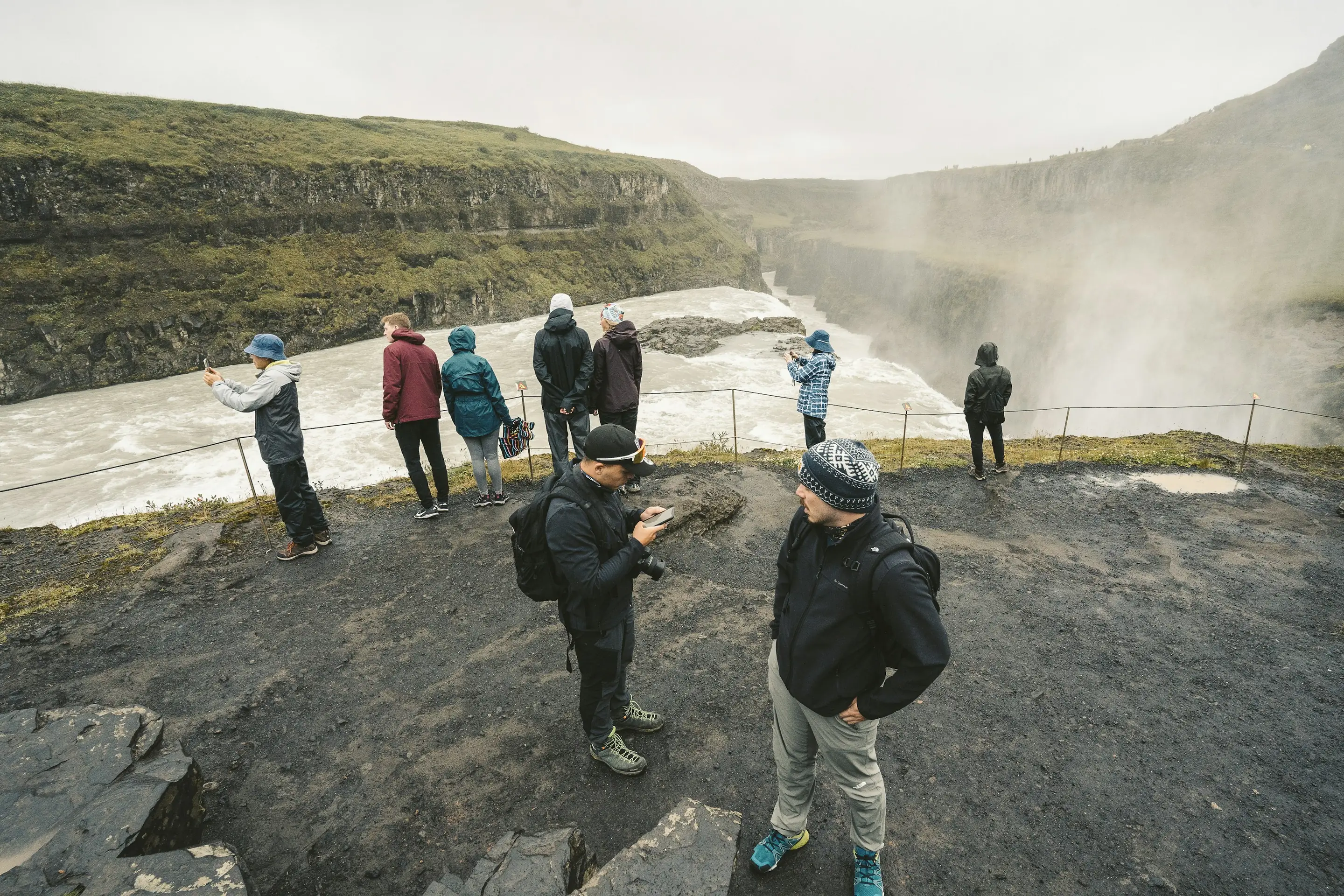 A group with their guide at the edge of the Gullfoss canyon